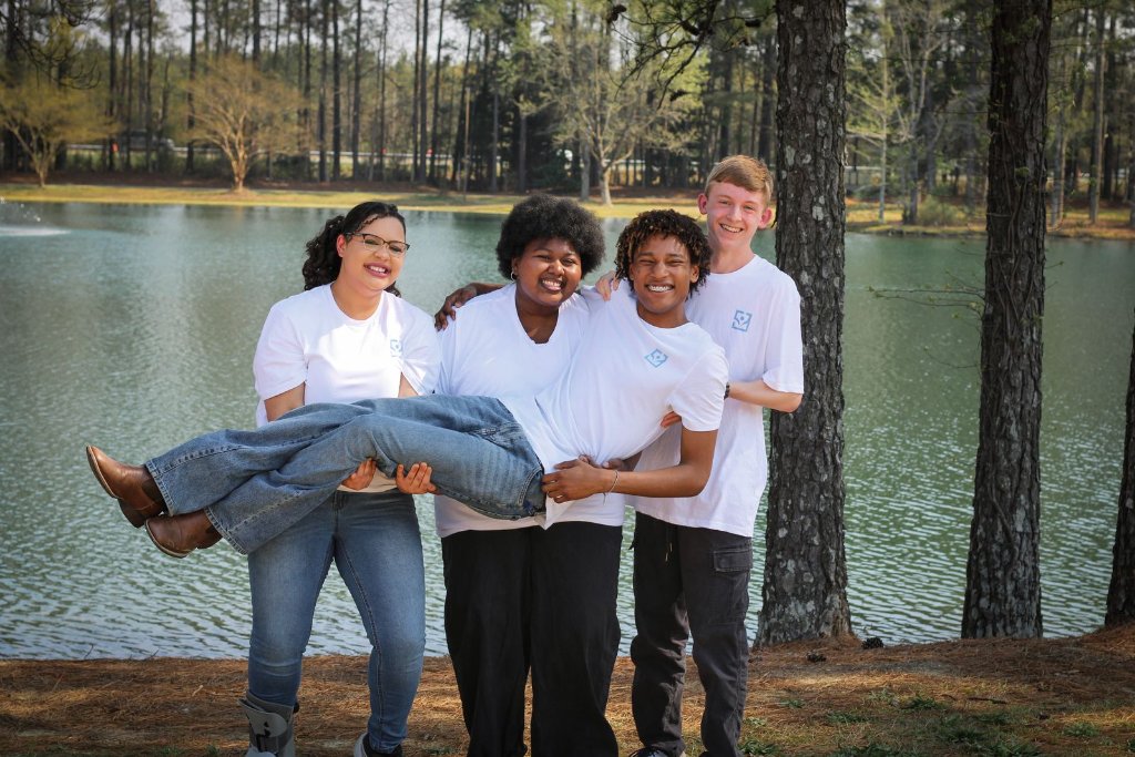Four EmpowerEd team members smiling together beside a lake
